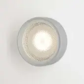 Round wall light, matte aluminum, recessed circular design with textured glass shade diffusing warm white light in a diamond pattern.
