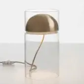 Table lamp, satin gold finish, with clear glass cylindrical base and rounded dome shade, supported by a curved brass arm.