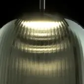 LED lamp with fluted glass shade, warm yellow light, chrome stem, modern design, translucent greenish tint, studio shot, black background.