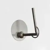 Wall lamp, satin black nickel, circular plate with cylindrical arm and angled stem, minimalist design, black cord, brushed metal texture.