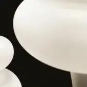 Frosted glass lampshades, varying sizes, rounded mushroom shape, translucent white material, cylindrical metal base, black background.