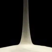 Frosted glass cone sculpture with a circular base, displaying vertical striations and a gradient from white to muted tones against black.