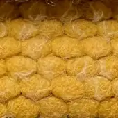 Puffo fabric sample, golden-yellow, densely woven with a fibrous, shredded texture in a honeycomb arrangement.