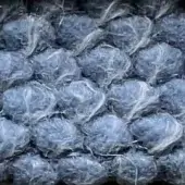 Textured plastic material, grayish-blue “puffo” color, displays rounded cellular forms with translucent, fibrous surface and irregular crinkled pattern.