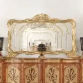 Exquisite Modenese Royal Blend mirror with ornate wood carvings and gold-colored finish including a cabinet with swirling floral motifs