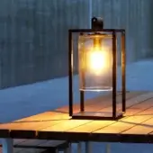 Distinguished Royal Botania Dome Small Table Lamp with black powder-coated aluminum frame and clear glass cylinder showcasing a warm glow
