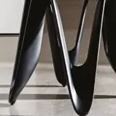 Cristalplant chair legs in black with matte finish, featuring sculptural curved design and pointed bases on gray tile flooring.