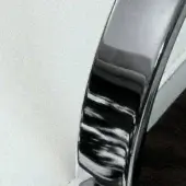 Chrome furniture component, polished metal with curved form, reflecting white surface and wood floor, Sovet Italia branding visible.
