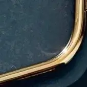 Polished brass frame with dark, textured interior; rectangular shape features curved edges and a circular indentation.