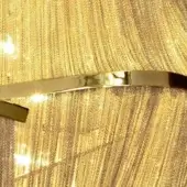 Terzani Atlantis cuff bracelet, gold-plated, rectangular band with inset detail, displayed against vertically-striped gold textile backdrop.