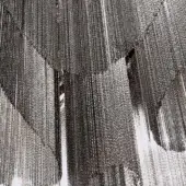 Metallic chain curtain, black nickel finish, cascading layers with diffused sheen and irregular gaps revealing bright background.