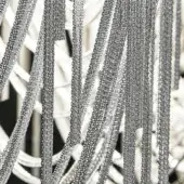 Metallic chain curtain, nickel-plated finish, vertical strands with white supports, textured surface, high contrast, diffused light reflection.
