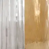 Glass sheets with vertical striations, one clear and reflective, one gold metallic with a distressed edge, studio lighting.