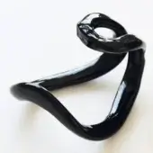 Black glass sculpture with looped form and curving arm, highly polished surface reflects light, minimalist white background.