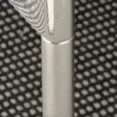 Chrome metal poles against perforated dark gray grid, cylindrical shape with connecting groove, diffused lighting highlights texture.