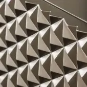 Triangular pattern, titanium-lacquered finish, metallic gray and silver tones, faceted rigid panel with reflective sheen, geometric three-dimensional structure.
