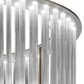 Chandelier, brushed silver metal, circular form with transparent glass rods, illuminated white light, thin gold accent ring, linear structure.
