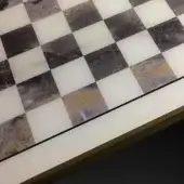 Marble chessboard tabletop with alternating white translucent & dark gray opaque squares, framed in dark metal with gold accent.