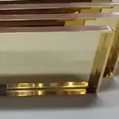 Gold metal panels stacked vertically with overlapping edges, featuring horizontal bars at the base and a polished, reflective surface.