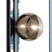 Glass wall sconce with dark bronze metal band, spherical shape, mounted on gray metal plate, illuminated interior, textured finish.