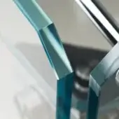 Cristallino Classic glass railing detail, teal-blue rectangular glass, polished chrome connectors, geometric design, studio lighting.