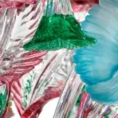 Glass sculpture with floral elements, clear glass, green bud, light blue bloom, silver stems, red and green accents, glossy finish.