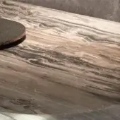 Resin tabletop with swirling brown and cream wood grain pattern, featuring a dark gray circular coaster on the polished surface.