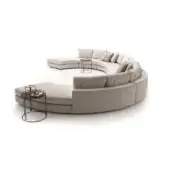 Beige curved sectional sofa, Loman Composition, modular design with circular arrangement, black metal side tables, studio setting.