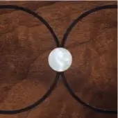 Concentric circle design, dark metallic rings, white center, on dark brown wood grain texture, geometric composition, studio shot.