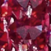 Red faceted object with triangular cuts, exhibiting bright white reflections and varied crimson tones against a blurred red backdrop.