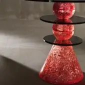 Side table, red resin, stacked organic form with three black glass circular tops, minimalist studio setting, mottled texture.