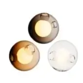 Spherical wall lights with smoky brown, amber, and clear glass shades, featuring circular indentations and warm interior illumination.