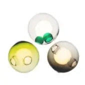 Blown glass wall lights, pale green, clear, and smoky gray, each with dual circular indentations emitting warm white light, studio lighting.