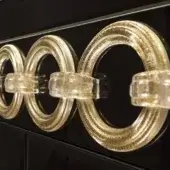 Gold ring chandelier with speckled texture, clear acrylic connectors, and warm lighting against a dark background.