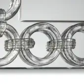 Transparent acrylic rings with rectangular textured bands, arranged in a sculptural, wave-patterned composition on a light gray surface.