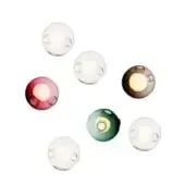 Spherical wall lights in clear, purple, brown, and teal glass with warm internal glow and circular openings against a white backdrop.