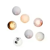 Glass sphere pendant lights in amber, rose, peach, and white tones feature circular perforations against a white backdrop.