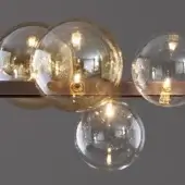Ceiling light fixture, glass globes, brass sockets, copper bar, warm Edison bulbs, varying amber hues, clear reflection, brushed metal finish.