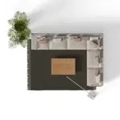 Beige modular sectional sofa with pink pillows on gray fringed rug, wood coffee table, palm plant, and white floor lamp in studio setting.