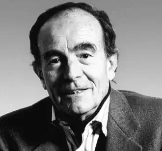 Monochrome portrait of a mature man with receding dark hair, wearing a textured jacket and loosened tie, facing slightly right with a gentle smile
