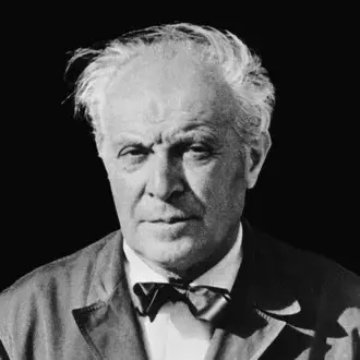 Portrait of a man in a dark tweed suit jacket, white shirt, and bow tie, with focused lighting and a black background.
