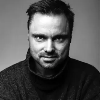Black and white portrait of Matti Klenell, a man with dark hair and beard wearing a gray turtleneck sweater, neutral expression.