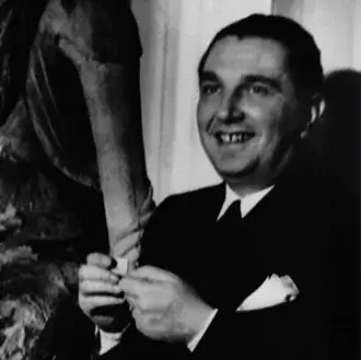 Pietro Chiesa portrait, man in dark suit, standing before textured abstract sculpture with curved arm, soft lighting, neutral background.