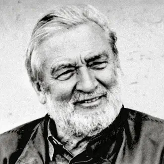 Verner Panton portrait, black and white photograph, showing a smiling man with white hair and beard, wearing a plaid jacket.