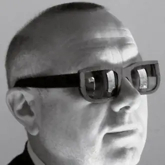 Head-mounted device, black and white, angular glasses with rectangular protrusions worn by Denis Santachiara in portrait.