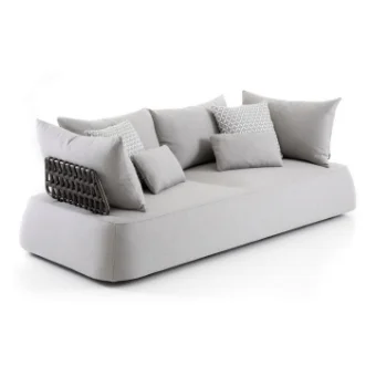 Light gray sofa with rounded cushions, arranged with textured pillows against a white backdrop in a studio setting.