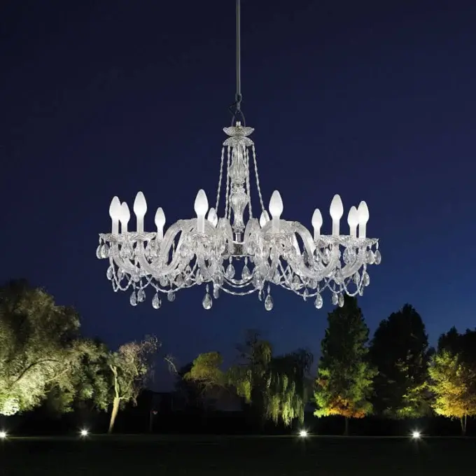 Masiero chandelier, crystal and metal, multi-tiered design with cascading pendants, suspended against a twilight sky with illuminated landscaping.