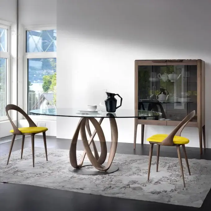 Glass dining table with walnut base, mustard chairs, and wood display cabinet in a modern dining room with gray rug.