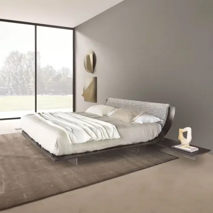 Bedroom with dark gray wood and metal platform bed, neutral linens, beige abstract wall art, and a textured brown area rug.