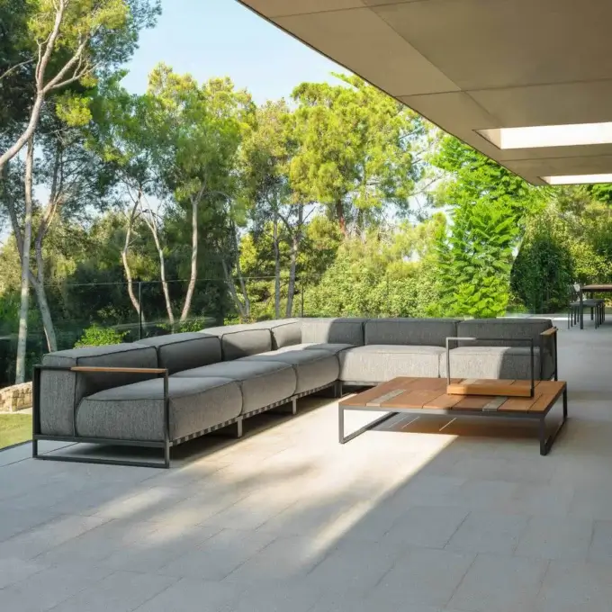 Talenti outdoor sofa, gray textured fabric, black metal frame with wood arms, arranged on light gray tile patio with wood coffee table.
